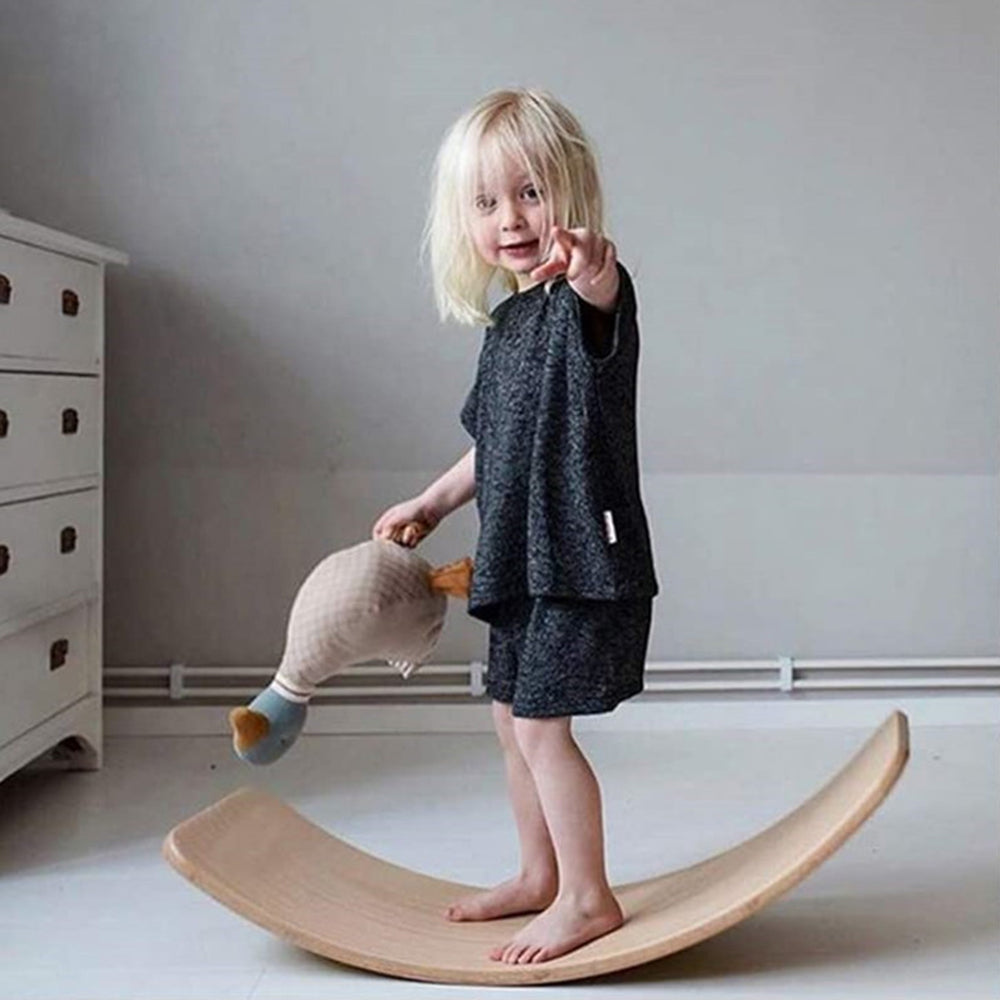 Children standing and balancing on curved wooden balance boards for sensory play