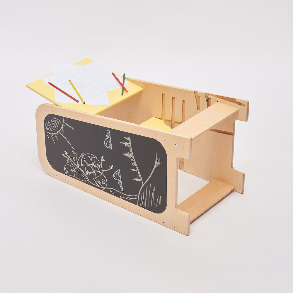 Montessori learning tower made of natural wood with a yellow side busy board, featuring interactive gears, sliders, and lockable elements for toddlers.