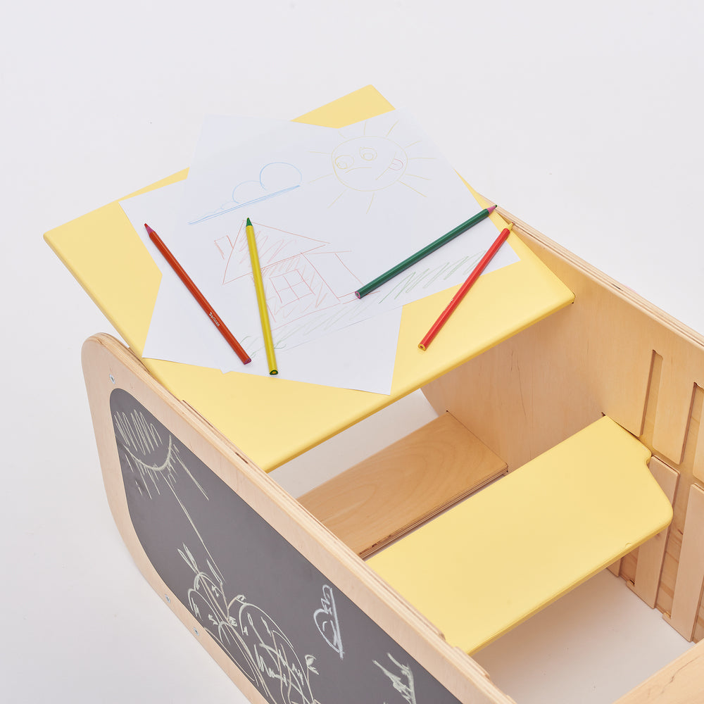 Montessori learning tower made of natural wood with a yellow side busy board, featuring interactive gears, sliders, and lockable elements for toddlers.