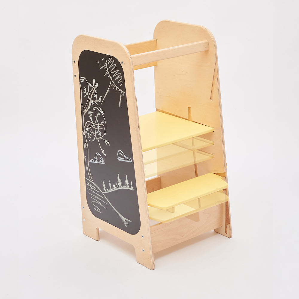 Montessori learning tower made of natural wood with a yellow side busy board, featuring interactive gears, sliders, and lockable elements for toddlers.